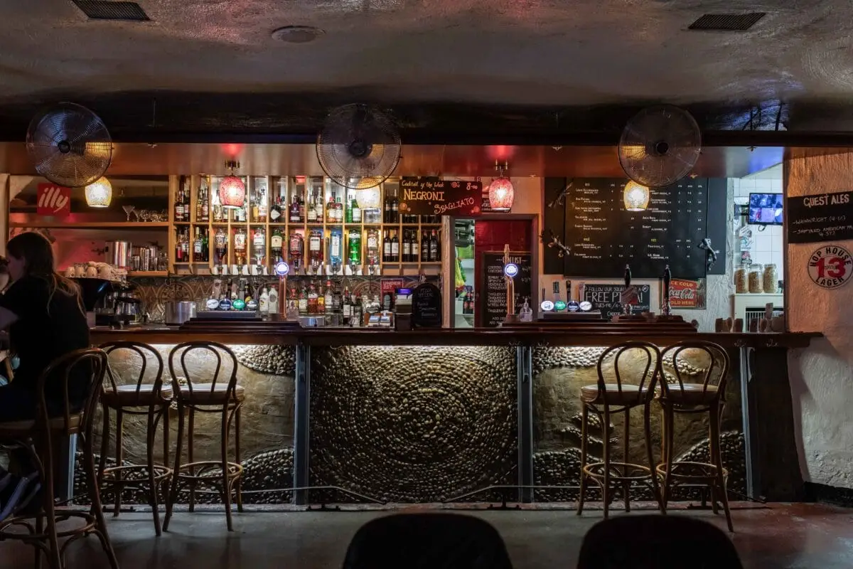 The inside of Corbieres wine bar in Manchester pictured with moody lighting and a tile stone mosaic decor with bar side seating