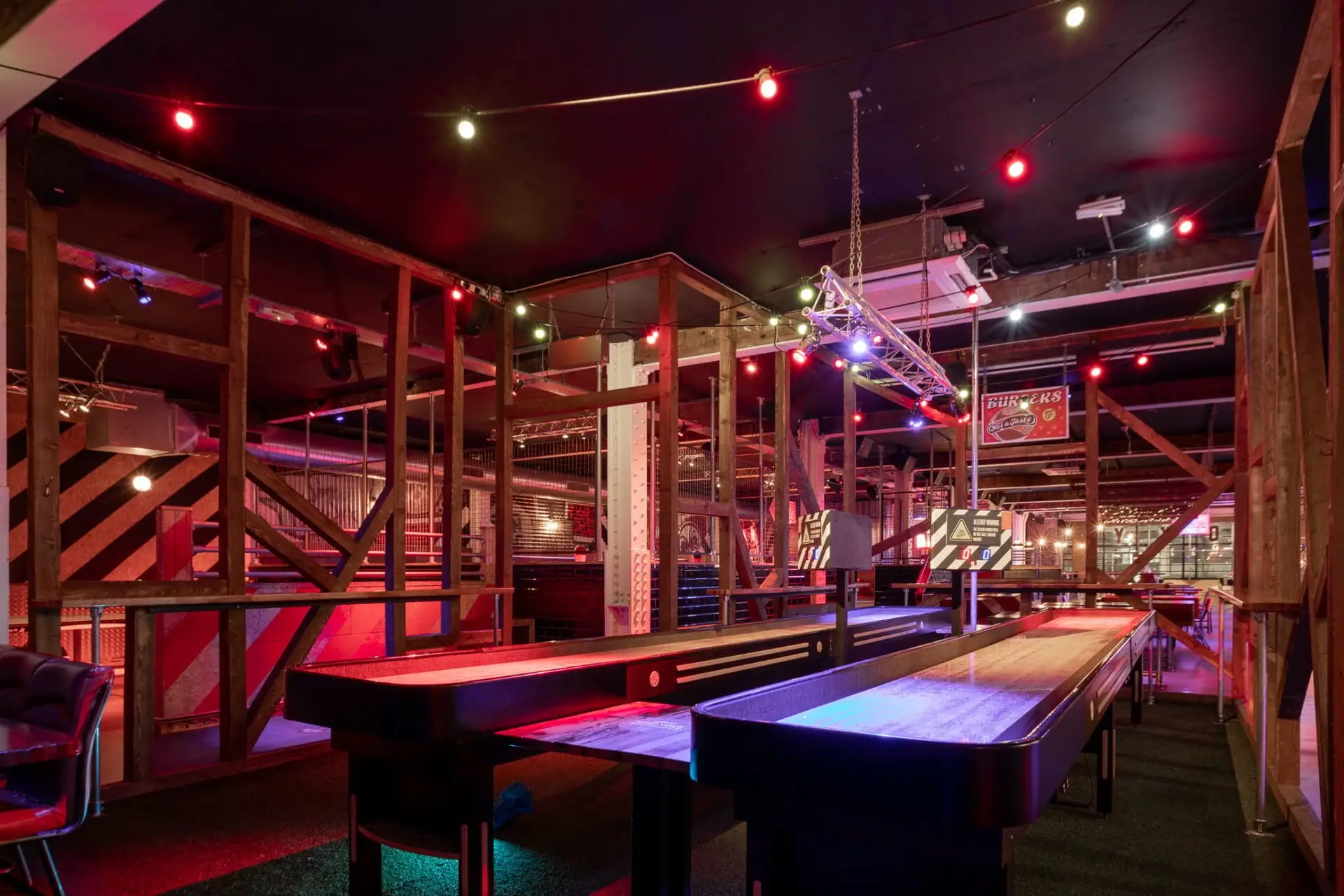 Shuffle boarding tables pictured at the Roxy Ballroom at night in Manchester with red lighting and wood interior