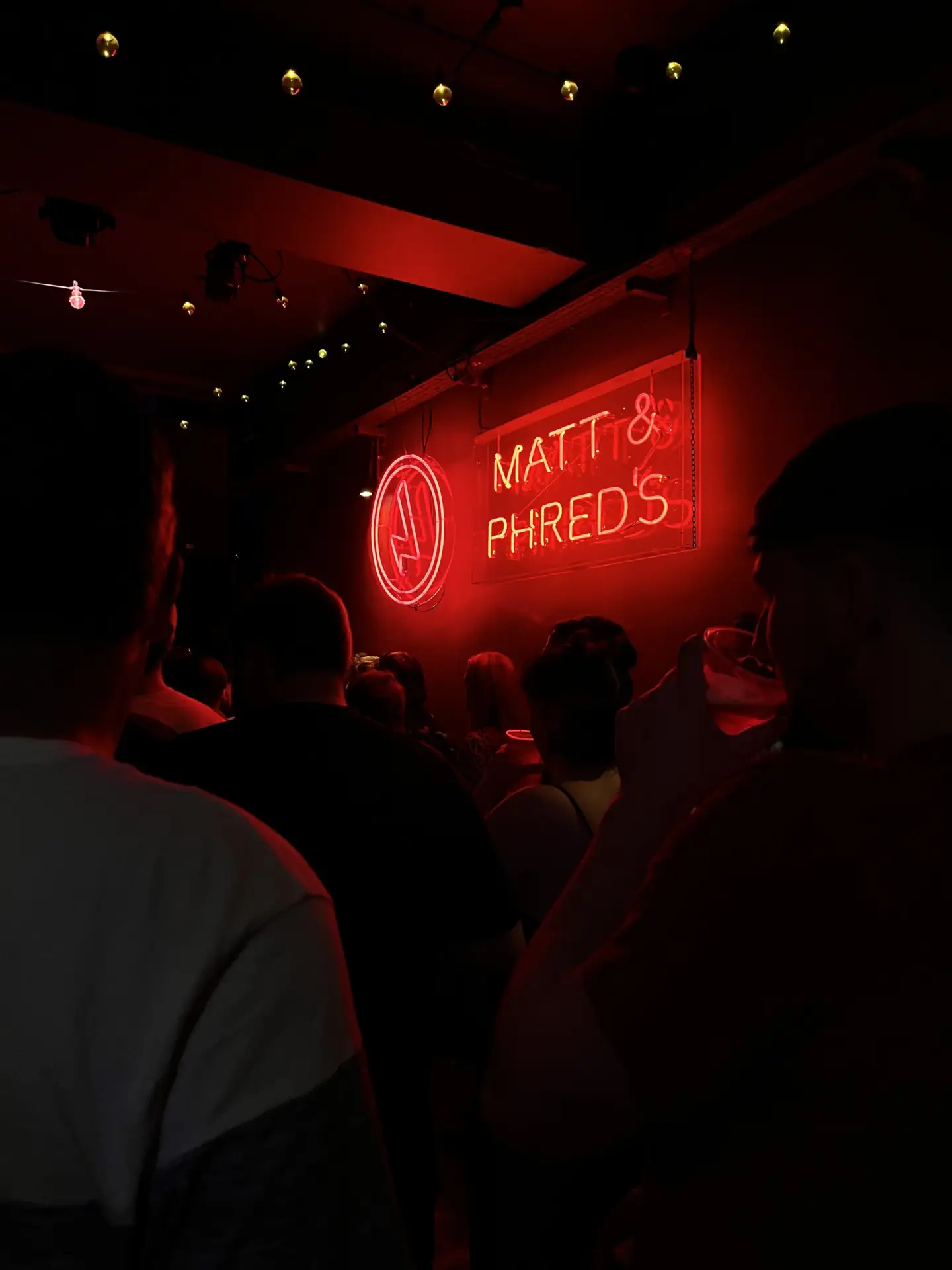 Neon red light sign inside Matt and Phred's Jazz Bar from a night in Manchester pictured above a crowd of people sitting for some live Jazz