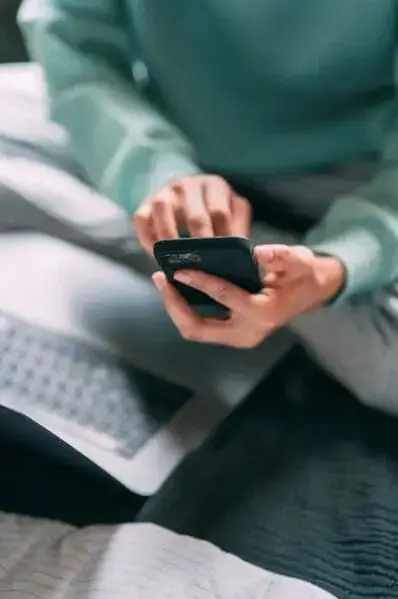 Unrecognizable man browsing smartphone on bed