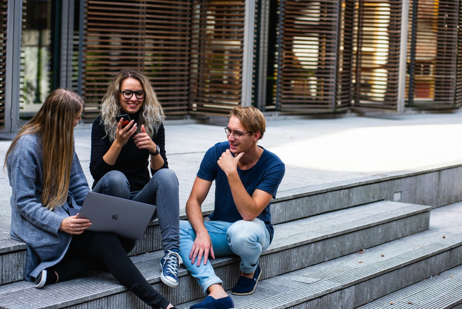 3 students sitting on steps outside