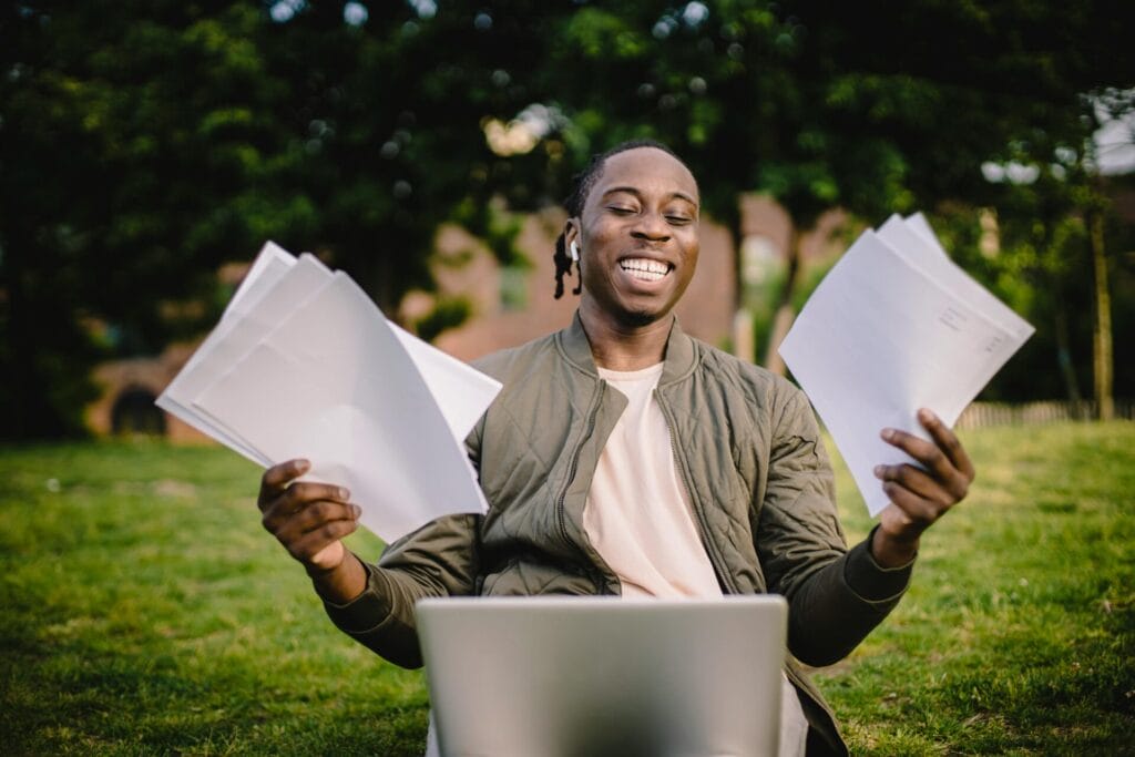 man holding papers happy in front of laptop