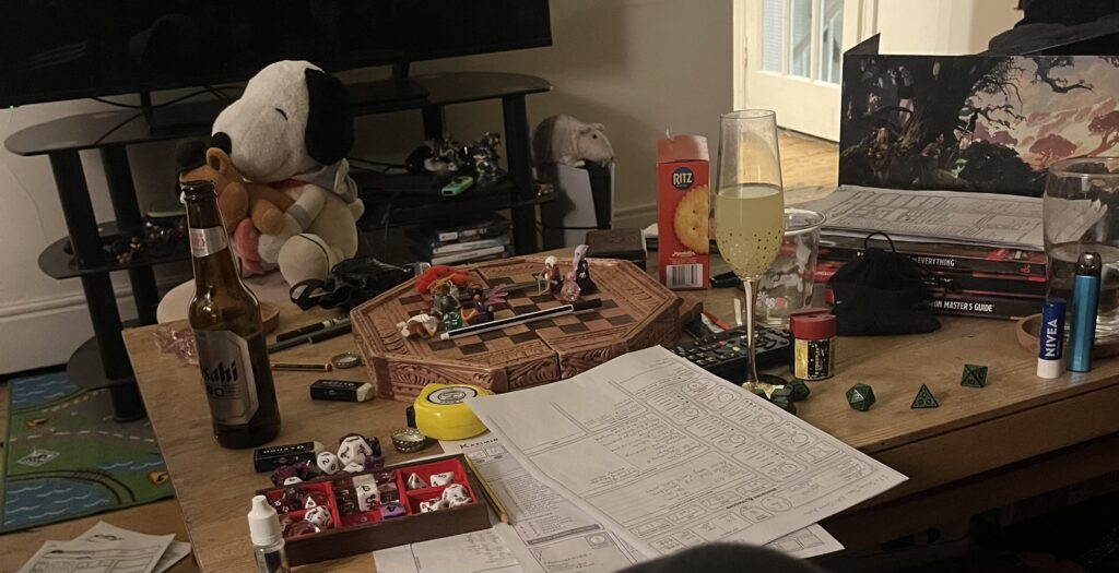 A living room table covered with a chess board, dice trays, and character sheets for a game of Dungeons and Dragons