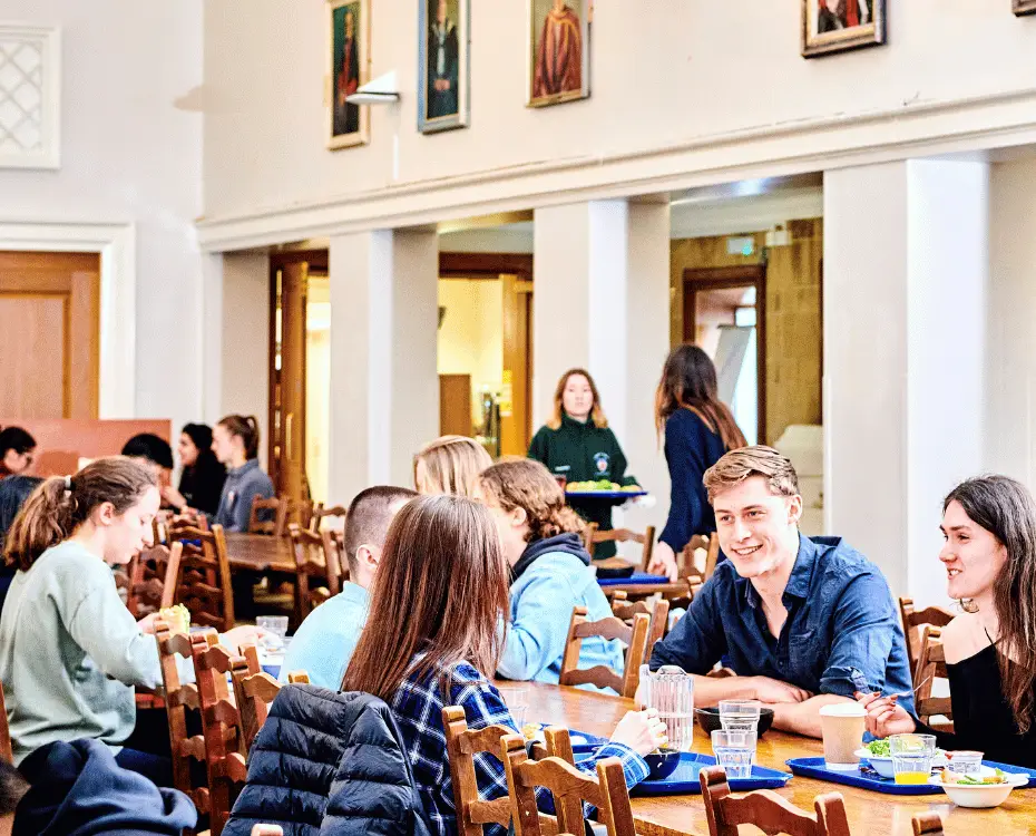 A dining scene at St. Mary's College, Durham University, a catered college. Students talk and smile during the mealtime.