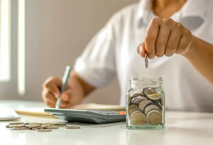 Person putting money into a jar representing savings