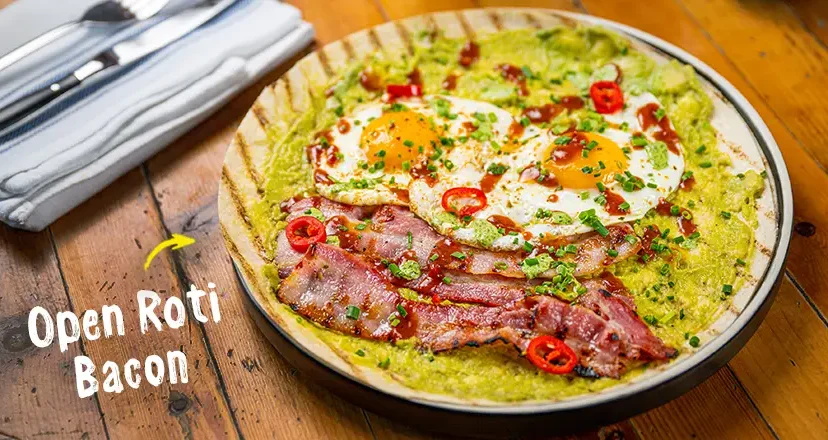 An open flatbread with bacon, eggs, and chillies. 