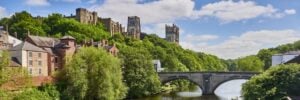 A view of Durham Castle and Cathedral over Framwellgate Bridge on a sunny day.