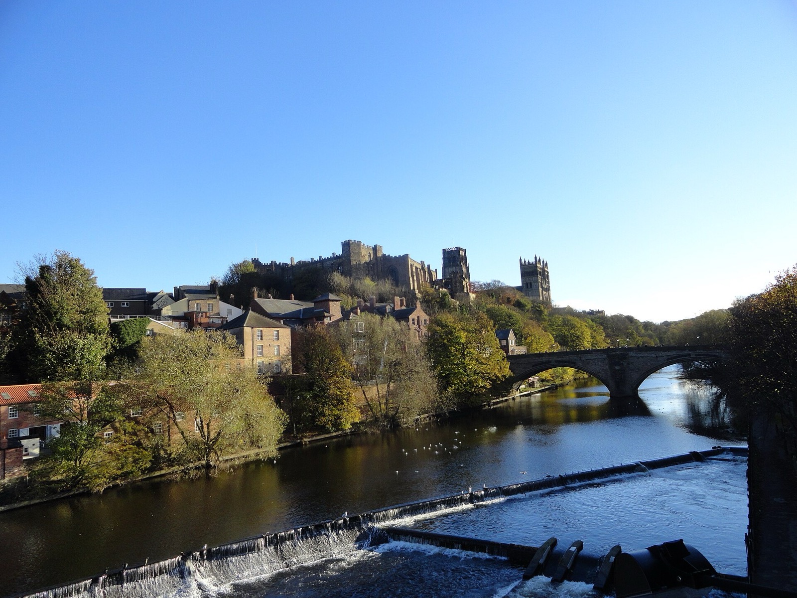 Durham Castle and Cathedral above the River Wear and Framwellgate Bridge under a blue sky