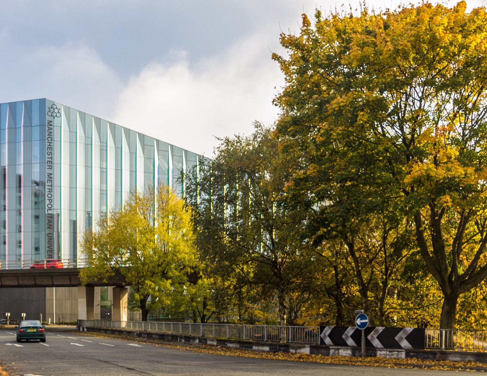 Manchester Metropolitan University's glass-fronted Business School framed by autumn trees