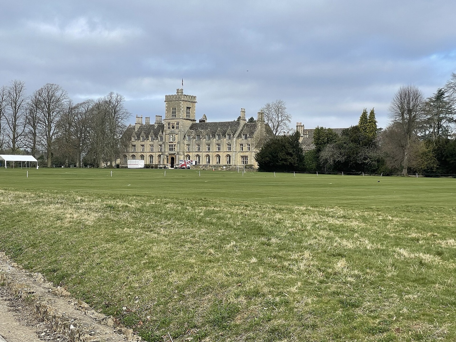 The Gothic-style main building of the Royal Agricultural University across open fields near Cirencester