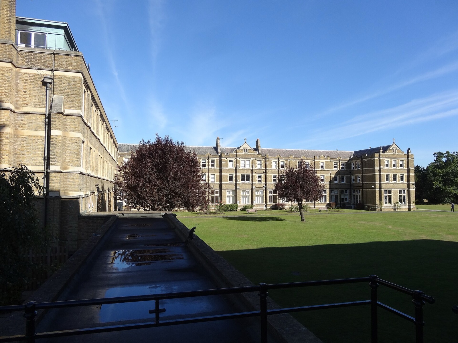 Historic buildings and lawn at St Mary's University, Twickenham, under a blue sky
