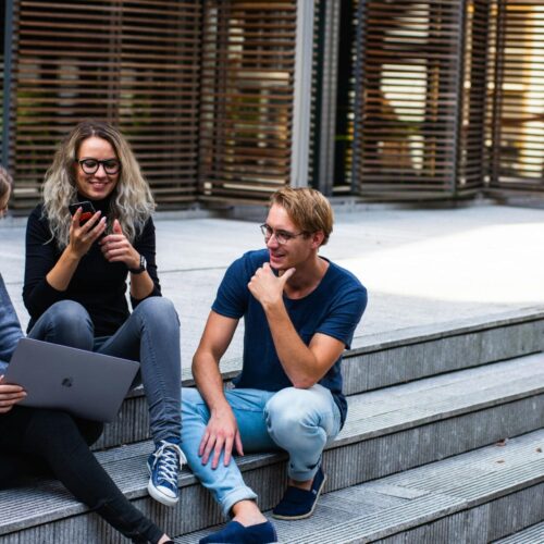 3 students sitting on steps outside